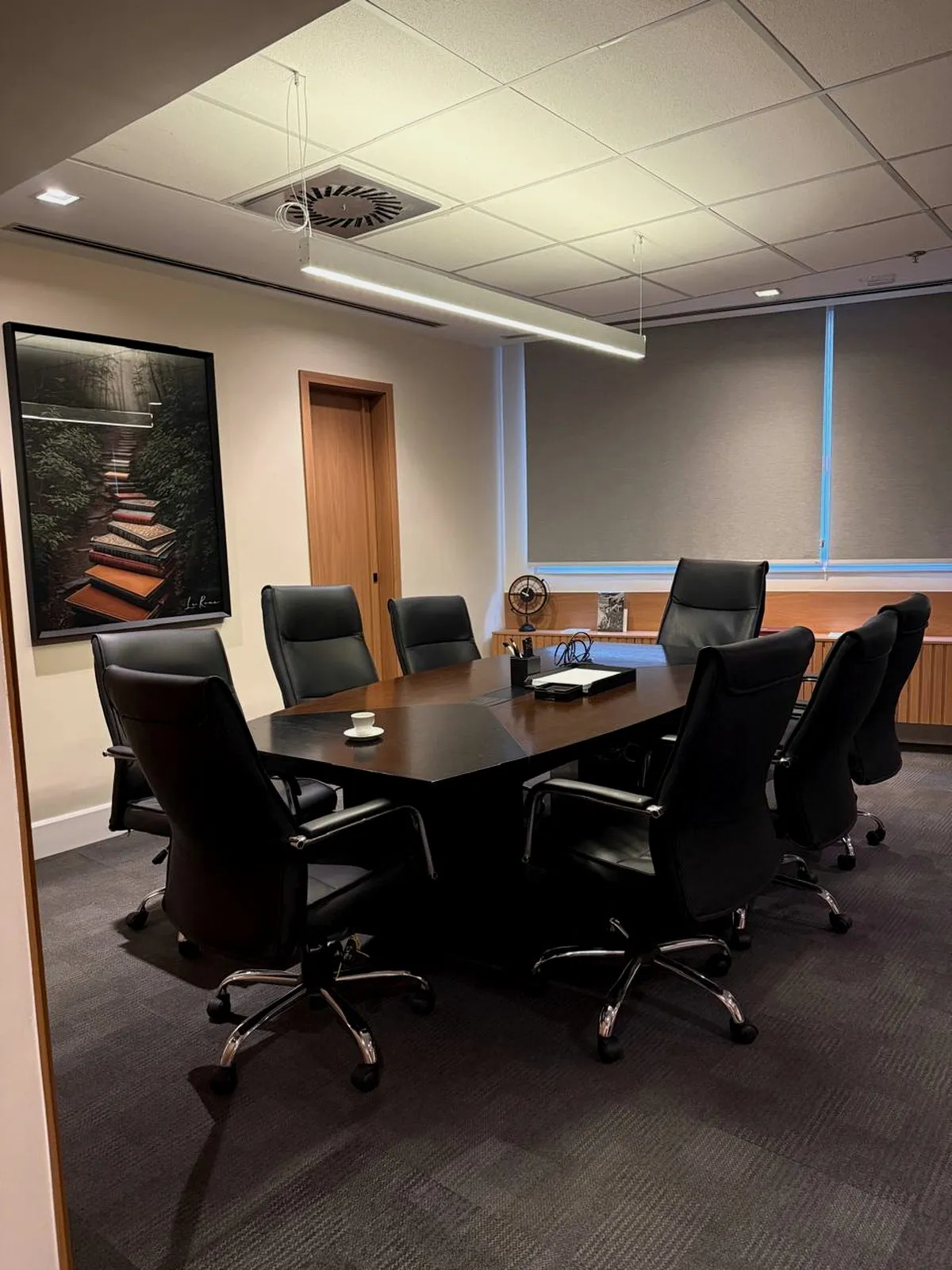 Sala de reunião ampla do escritório, com mesa escura e cadeiras executivas pretas